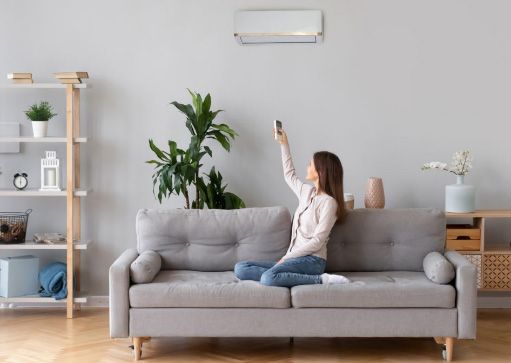 woman controlling a ductless mini split AC unit from her living room couch